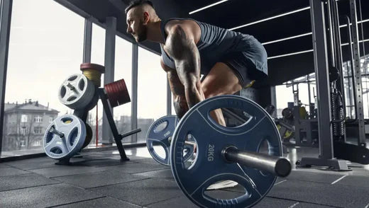 Homme dans une salle de sport en train d'exécuter un mouvement de soulevez de terre avec une barre olympique