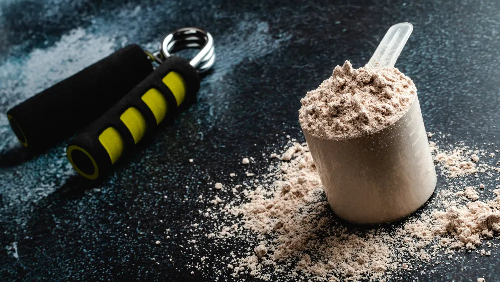 Une scoop rempli de protein avec un équipement de musculation à côté