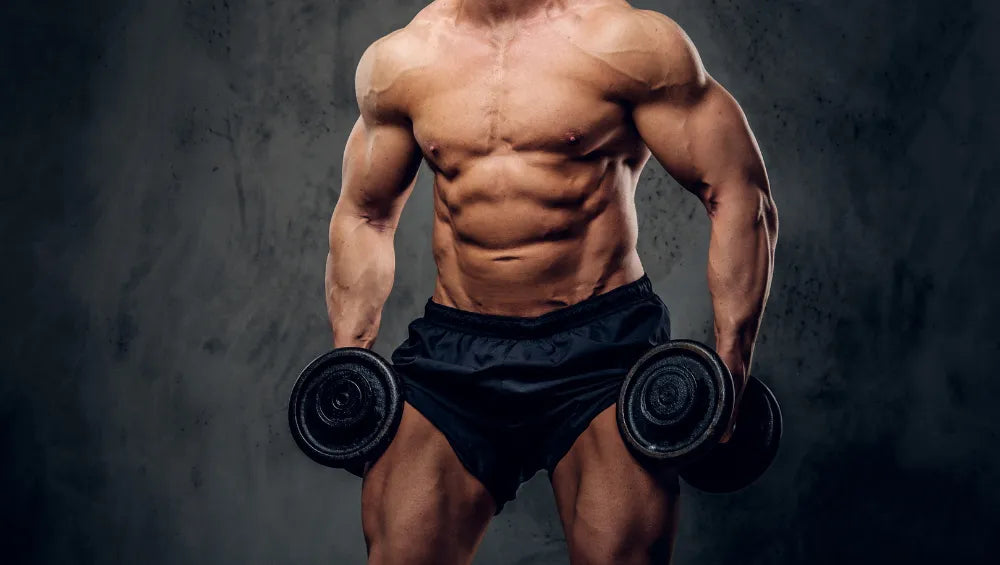 Homme musclé torse nu en short avec des haltères à la main sur un fond sombre gris