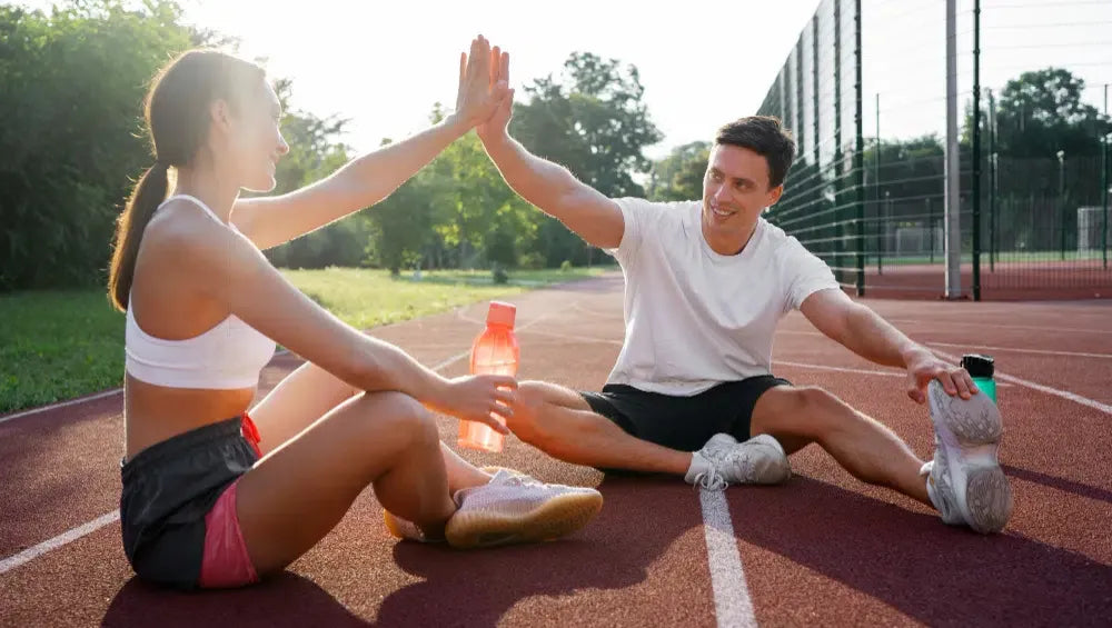 Un Homme et une Femme sur une piste olympique assis ce tapant la main