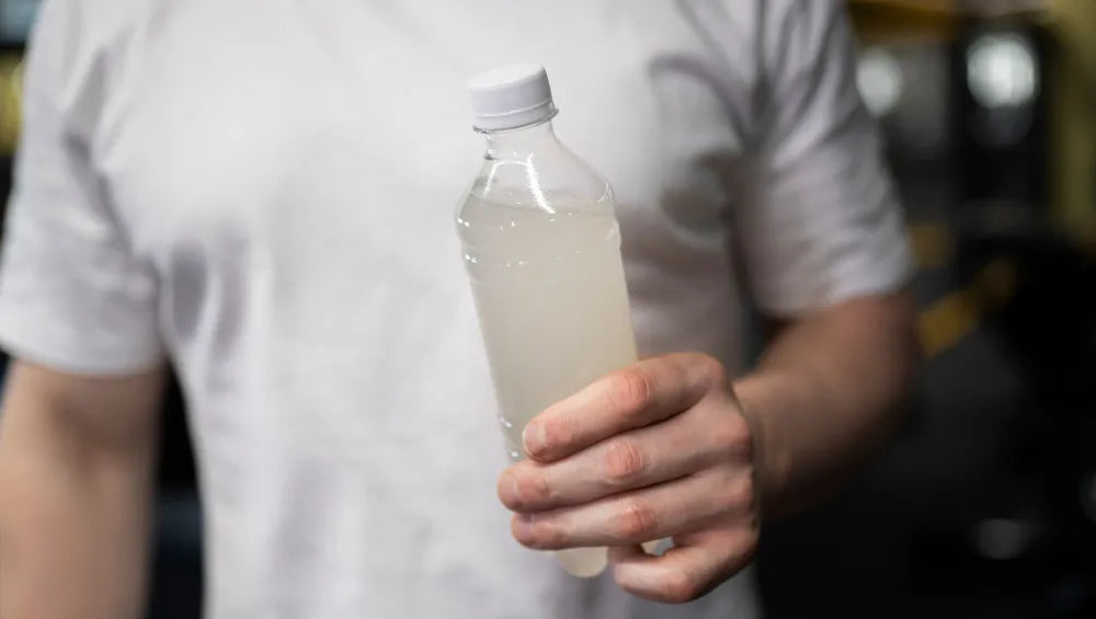 Un homme en t-shirt blanc portant dans la main une bouteille avec des vitamines 